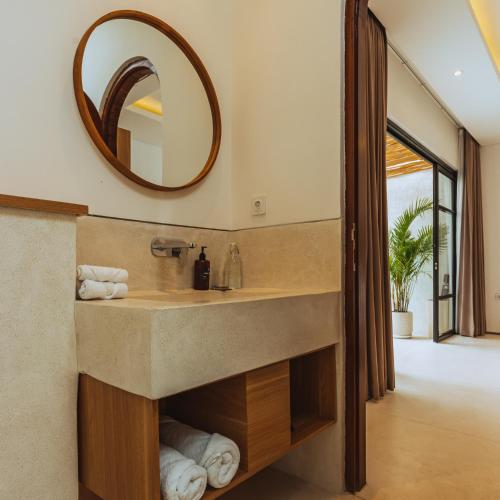 ein Bad mit einem Waschbecken und einem Spiegel in der Unterkunft The Serendipity Palms Villa by Hombali in Canggu