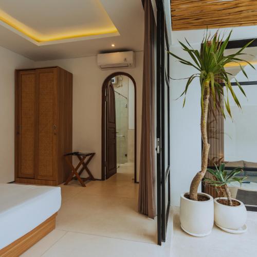 ein Schlafzimmer mit einem Bett und einer Topfpflanze in der Unterkunft The Serendipity Palms Villa by Hombali in Canggu