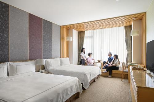 a hotel room with two beds and people sitting at Evergreen Resort Hotel - Jiaosi in Jiaoxi