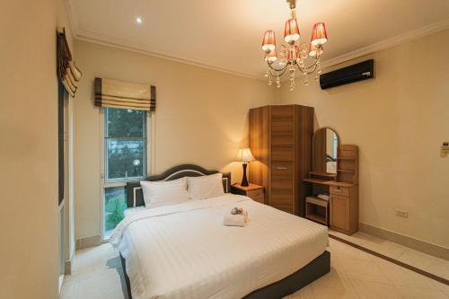 IvyRich Pool Villa Chiang Mai في هانغدونغ: غرفة نوم بسرير ابيض كبير وثريا