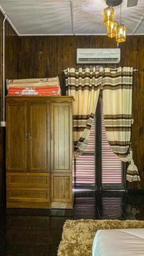 a bedroom with a dresser and a window with curtains at Aaira 8Pari Riverview Lodge in Kota Bharu