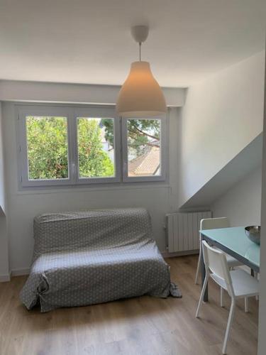 une chambre avec un lit et une table et deux fenêtres dans l'établissement Joli studio au calme en bord de mer #pornichouette, à Pornichet
