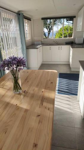 a kitchen with a vase of flowers on a wooden table at Serenity Alpaca Self Catering Cottage in Lions River