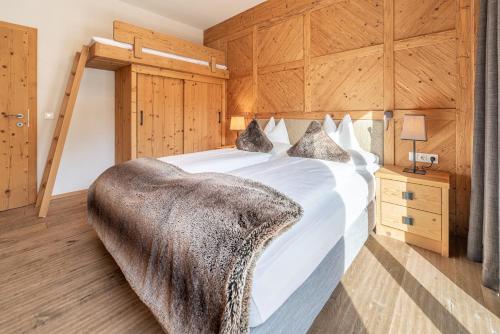 a bedroom with a large white bed with wooden walls at Gletscherblick- serviced apartments in Obergurgl