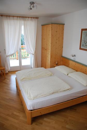 a large bed in a room with a large window at Affittacamere Dai Stoneri in Cavareno