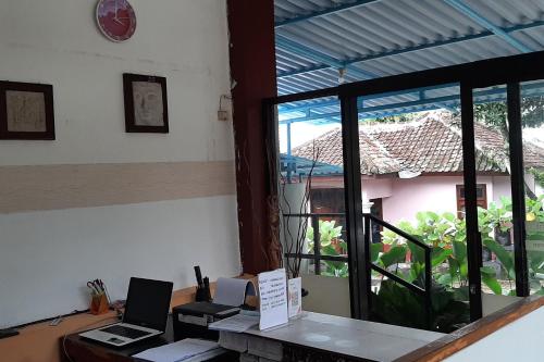 RedDoorz At Hotel Pakem Sari Kaliurang في Pakem: مكتب به جهازين لابتوب على مكتب مع نافذة