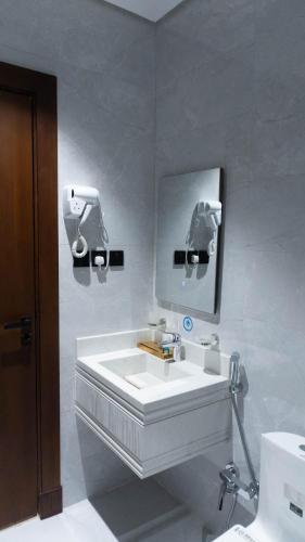 ein weißes Badezimmer mit Waschbecken und Spiegel in der Unterkunft Aldar Apartments in Riad