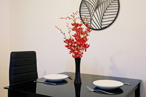 a black table with a vase with red flowers on it at Mishuku Onna 103 in Baba