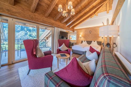 a bedroom with a bed and a couch and chairs at Gletscherblick- serviced apartments in Obergurgl