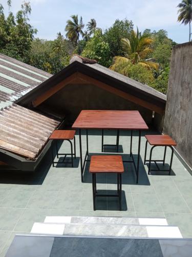 two tables and two stools on a roof at Bee Line Cinnamon Estate Villa in Dickwella