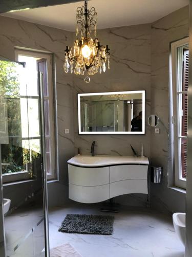 een badkamer met een bad, een spiegel en een kroonluchter bij château de Puymoger in Javerlhac-et-la-Chapelle-Saint-Robert