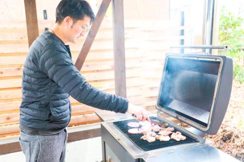 a man is cooking food on a grill at 忍野八海まで車で４分！ワンランク上のアウトドアライフ堪能できる【LongevityVillage】B in Minamitsuru