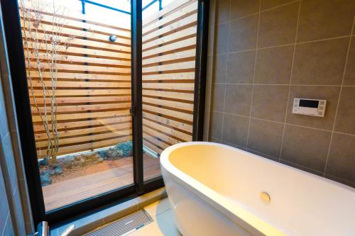 a bathroom with a tub and a window with wooden blinds at 忍野八海まで車で４分！ワンランク上のアウトドアライフ堪能できる【LongevityVillage】B in Minamitsuru