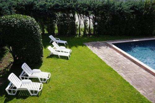 a group of white chairs sitting next to a swimming pool at Hotel Diana in Riva del Garda