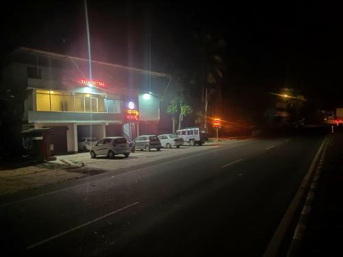 a street at night with cars parked in front of a gas station at Dhanya Lodge in Padubidri