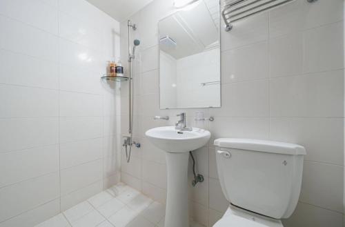 a white bathroom with a toilet and a sink at Manhattan Hotel in Jeju