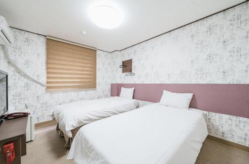 two beds in a room with white and purple at Manhattan Hotel in Jeju