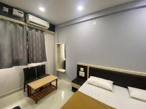 ein kleines Zimmer mit einem Bett, einem Tisch und einem Fenster in der Unterkunft Dhanya Lodge in Padubidri
