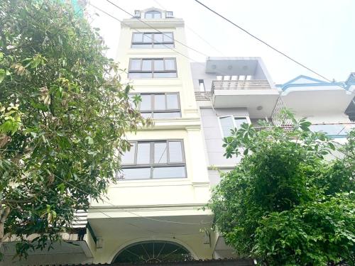 un bâtiment blanc avec des arbres devant lui dans l'établissement Blue Rose Hotel, à Hạ Long