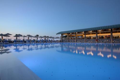 uma grande piscina de água com cadeiras e guarda-sóis em Arina Beach Resort em Kokkíni Khánion
