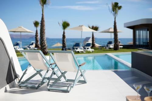 a pair of chairs sitting next to a swimming pool at Arina Beach Resort in Kokkíni Khánion