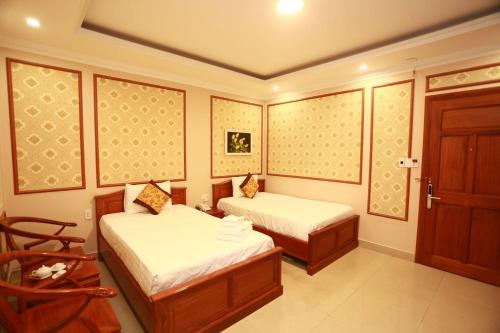 a small room with two beds and a chair at THANH TAI HOTEl 1 in Ho Chi Minh City