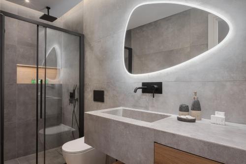 a bathroom with a sink and a toilet and a mirror at Athenian Riviera Seaside Suite in Athens