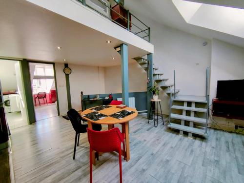 een kamer met een tafel en stoelen en een trap bij Home - Sous les toits de Paris - Séjour à Auxerre in Auxerre