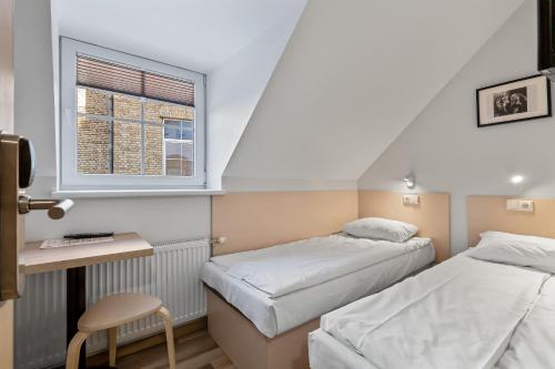 een kamer met 2 bedden, een bureau en een raam bij Stay Express in Vilnius