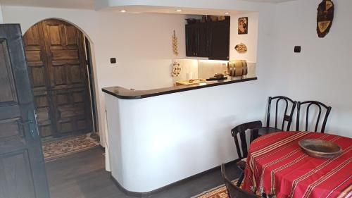 Zimmer mit einem Tisch und einer Küche mit einer Tür in der Unterkunft Къща за гости -Абаджиевата къща in Kotel