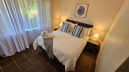 a bedroom with a bed with pillows and a window at Grobler's Haven in Pretoria