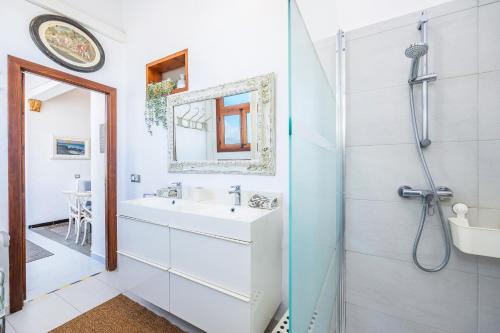 a white bathroom with a sink and a mirror at Poppy's Beach House in Colònia De Sant Jordi