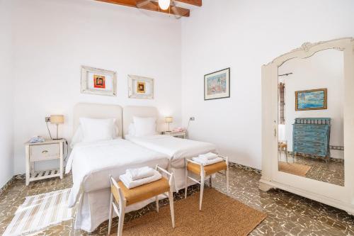 a bedroom with a large white bed and a mirror at Poppy's Beach House in Colònia De Sant Jordi