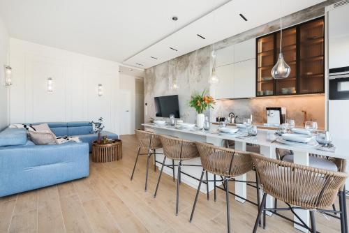 a kitchen and a living room with a blue couch at Sol Marina Resort Wyspa Sobieszewska I - LoftAffair Collection in Wiślinka