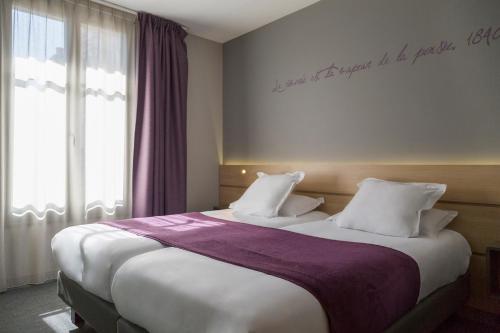 a hotel room with two beds and a window at Hôtel du Château Dinan - Originals Boutique in Dinan