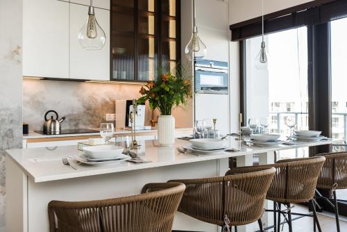 a kitchen with a long counter with chairs and tables at Sol Marina Resort Wyspa Sobieszewska I - LoftAffair Collection in Wiślinka