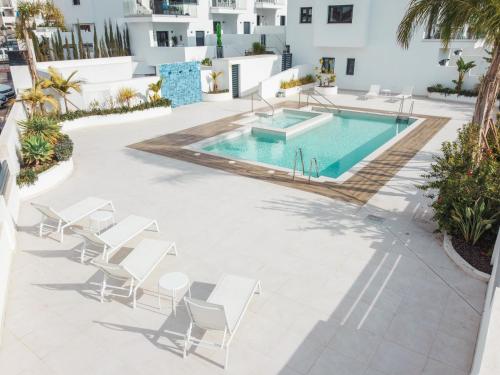 um pátio com uma piscina e cadeiras e uma piscina em New Luxurious house with rooftop terrace and pool em Nerja