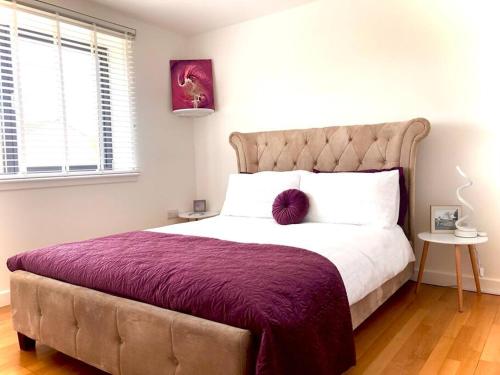 a bedroom with a large bed with a purple blanket at Keppochhill - Beautiful Home with Hot Tub in Dullatur