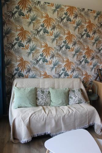 a couch in a living room with a floral wallpaper at Studio Le Cosy in Montrichard