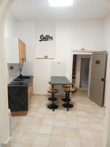 une cuisine avec une table et des tabourets dans une pièce dans l'établissement Les halles de Béziers, à Béziers
