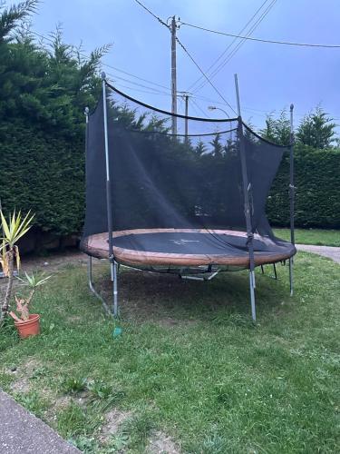 a trampoline with a net on the grass at Logement entier limay in Limay