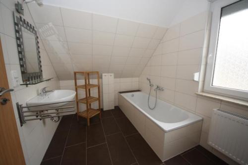 ein Badezimmer mit einem Waschbecken, einer Badewanne und einem Spiegel in der Unterkunft K 95 - Modernes Ferienhaus mit Kamin in Roebel an der Mueritz in Marienfelde