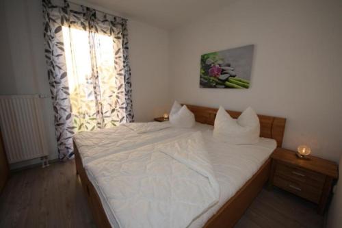 - une chambre avec un lit doté de draps blancs et une fenêtre dans l'établissement K 97 - stilvolles Ferienhaus mit Kamin & WLAN am See in Röbel an der Müritz, à Röbel