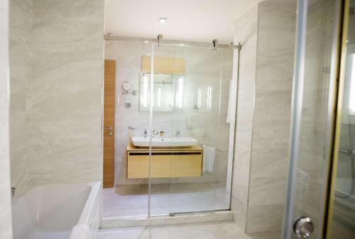 a bathroom with a tub and a sink and a shower at Best Western Premier Ark Hotel in Tirana