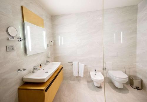 a white bathroom with a sink and a toilet at Best Western Premier Ark Hotel in Tirana