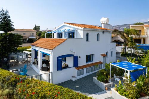 a white house with blue windows and a roof at Azure Luxury Villa by Nomads in Peyia