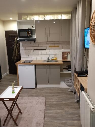 - une cuisine avec des placards blancs, un évier et une table dans l'établissement Appartement 2 pièces a louer, à Saint-Denis