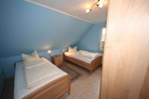 Duas camas num quarto com paredes azuis em K77 - 5 Sterne Ferienhaus mit Sauna, grossem Garten direkt am See in Roebel an der Mueritz em Marienfelde