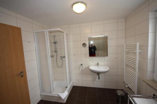 a bathroom with a shower and a sink and a mirror at K77 - 5 Sterne Ferienhaus mit Sauna, grossem Garten direkt am See in Roebel an der Mueritz in Marienfelde