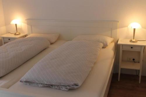 2 Betten in einem Zimmer mit 2 Lampen an Tischen in der Unterkunft K 104 EG - moderne Ferienwohnung am See mit Sauna & Kamin in Marienfelde